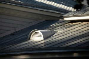 Rain falls on a residential roof while insulated attic space and ceiling materials reduce sound indoors.